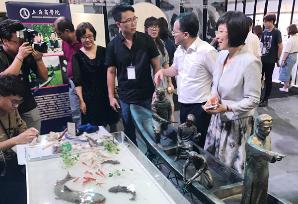 图为教育部体卫艺司副巡视员万丽君及市教委副主任倪闽景等领导  观看我校全国第五届大学生艺术展演“陶艺工作坊”展区